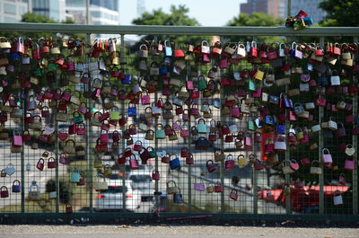 Colorful padlocks on bridge railing in city