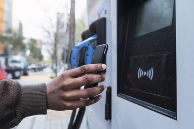 Hand of man paying through smart phone at charging station