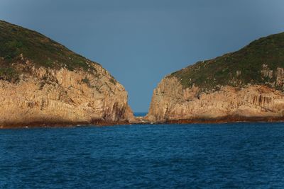 Scenic view of sea and mountains against clear blue sky