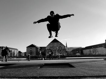 Man jumping in city against clear sky
