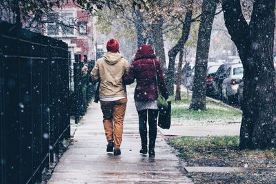 Rear view of people walking on street during snowfall