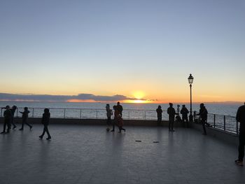 Silhouette people on beach against sky during sunset