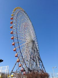 Low angle view of ferris wheel against clear blue sky