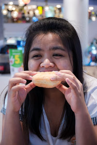 Close-up portrait of young woman eating donut