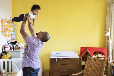 Happy man picking up son while standing at home