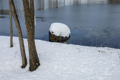 Snow covered wooden post in lake