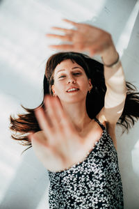 Portrait of smiling young woman gesturing against wall