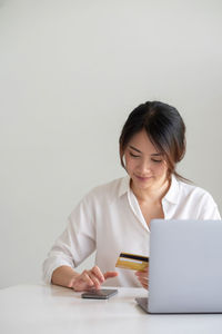 Mid adult woman using mobile phone while sitting on table