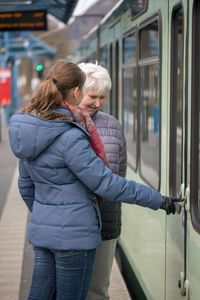 Granddaughter teaching grandmother opening door of train