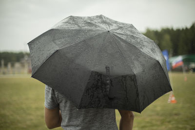 Rear view of woman with umbrella standing against sky