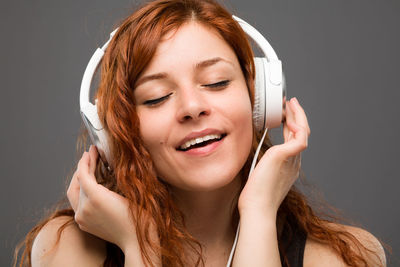 Portrait of smiling young woman using smart phone against black background