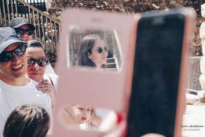 Reflection of young woman using mobile phone in mirror