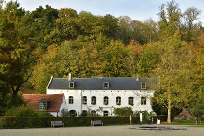 Built structure by trees and houses against sky