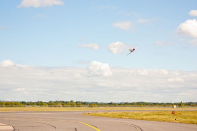 Airplane flying over road against sky