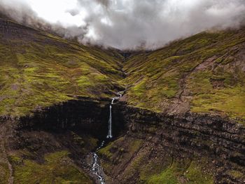 Scenic view of stream amidst mountains against sky