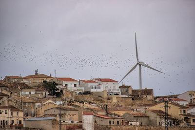 View of cityscape against sky with birds flying 