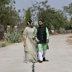 Full length portrait of young couple standing against plants