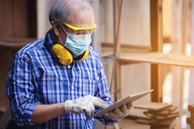 Male carpenter in a construction workshop, using a digital tablet