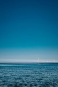 Sailboat sailing in sea against blue sky