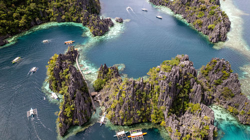 In the photo, a vibrant tropical boat near a beautiful beach or rocky shore.