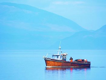 Fishing boat sailing in sea against sky