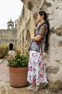 Side view of woman standing against building