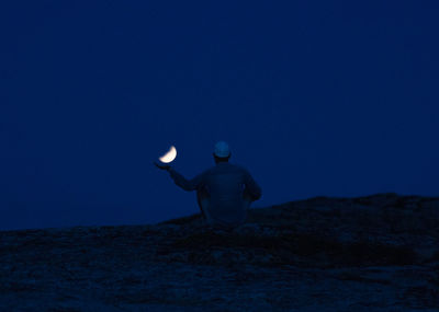 Rear view of man standing against moon in sky