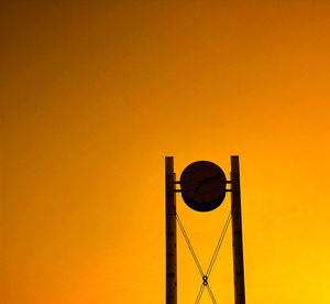 Low angle view of silhouette pole against orange sky
