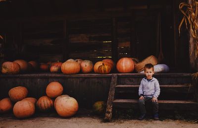 Portrait of boy sitting on steps against pumpkins