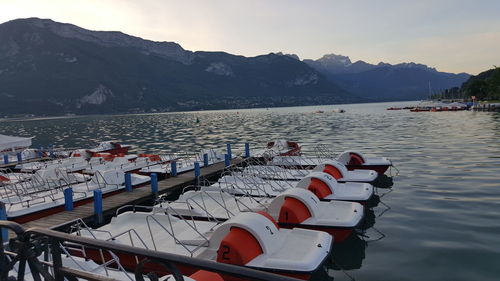 Boats moored on sea by mountains against sky