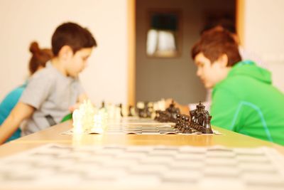 Boys playing chess on table at home