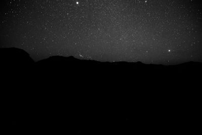 Scenic view of silhouette mountains against sky at night