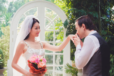 Married couple holding bouquet sitting outdoors