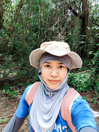 Portrait of woman wearing hat standing in forest
