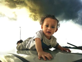 Portrait of cute boy looking away against sky