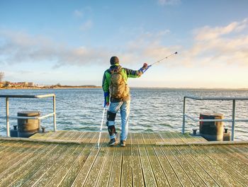 Rear view of man fishing on sea against sky