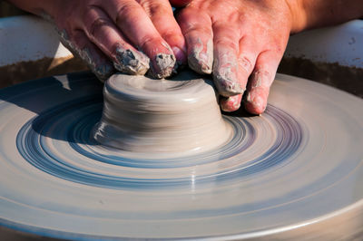 Cropped hands of man molding a shape on pottery wheel