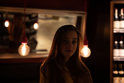 Portrait of woman with illuminated light bulbs in cafe