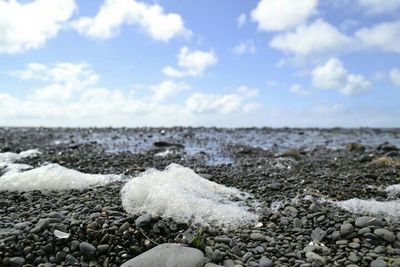 Rocks on beach against cloudy sky