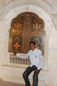 Full length portrait of young man standing against building