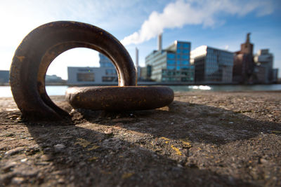 Close-up of rusty metal by street against sky