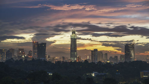 Modern buildings in city against sky during sunset