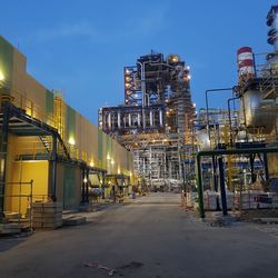 Illuminated factory against sky at night