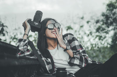 Full length portrait of young woman sitting outdoors