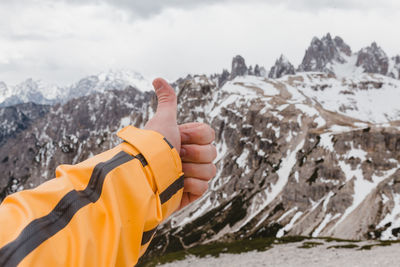 Close-up of hand showing thumbs up against sky