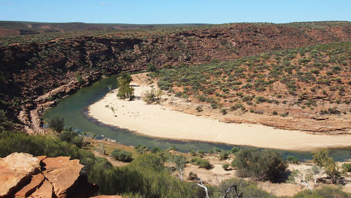 Scenic view of river by mountains against clear sky