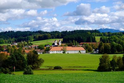 Houses on field against cloudy sky