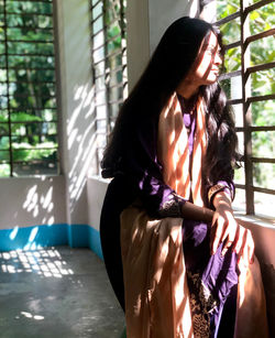 Young woman sitting on window sill