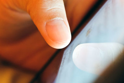 Cropped finger of person touching mobile screen