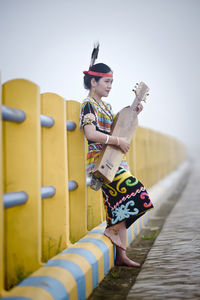 Boy standing by railing against sky